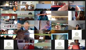 Zoom screenshot featuring many people holding up to the camera a long object horizontally, such as a pencil or drumstick
