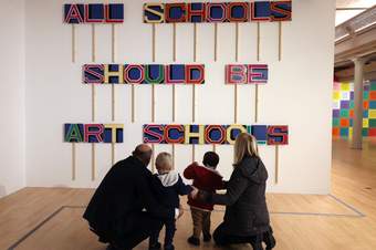 A photograph of a family looking at an artwork by Bob and Roberta Smith