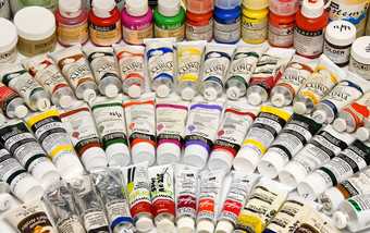 Many tubes and pots of paint displayed in arcs on a flat surface