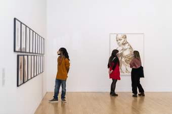 Three visitors look at artwork at Tate Britain