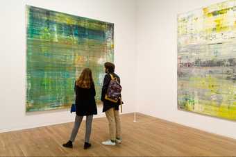 Two visitors in the In the Studio display at Tate Modern looking at a large painting.