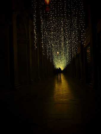 A photograph taken alongside the Piazza San Marco, where light creates a pathway in the dark for the couple in the frame